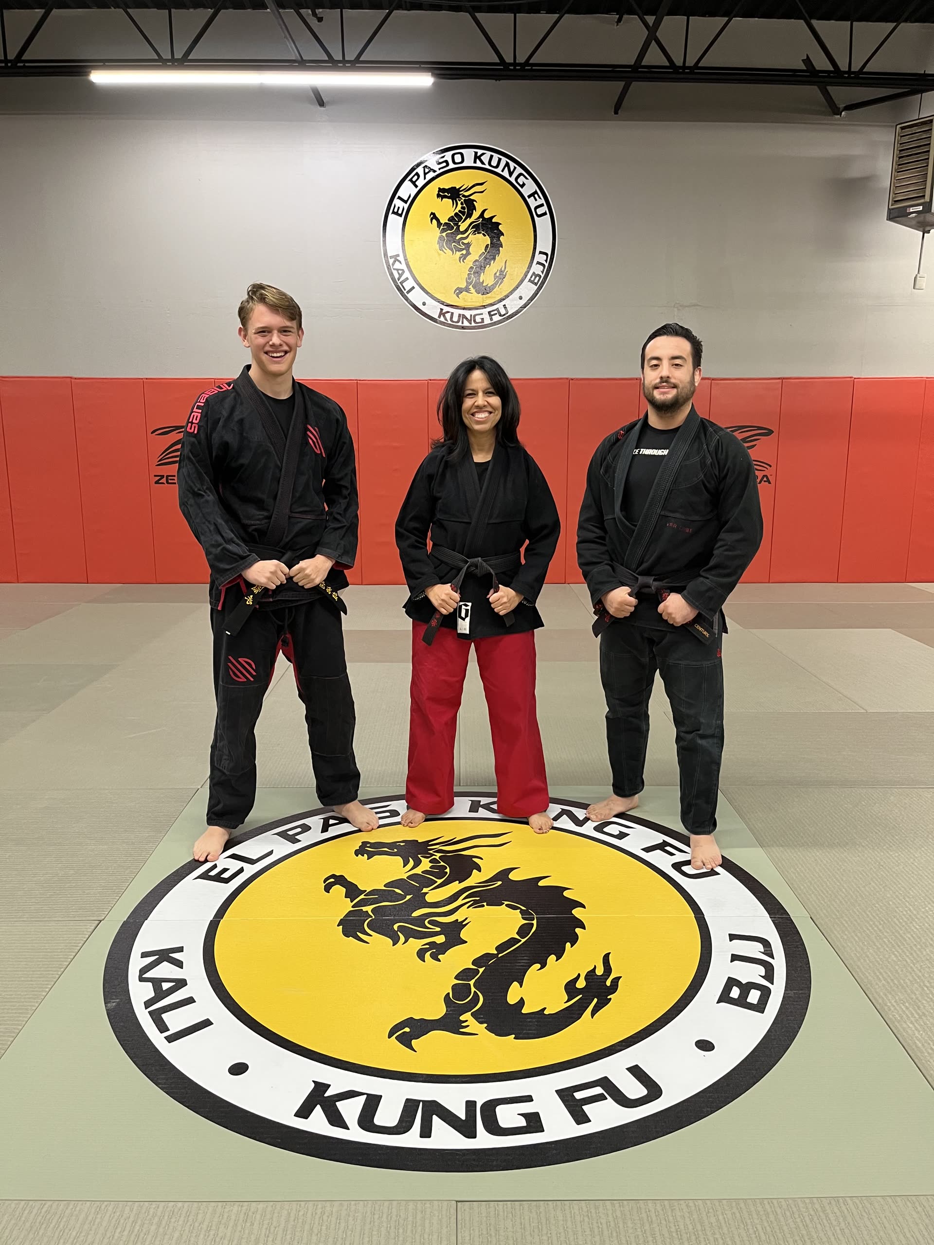 Instructors and staff of El Paso Kung Fu standing together on the academy's dragon logo mat
